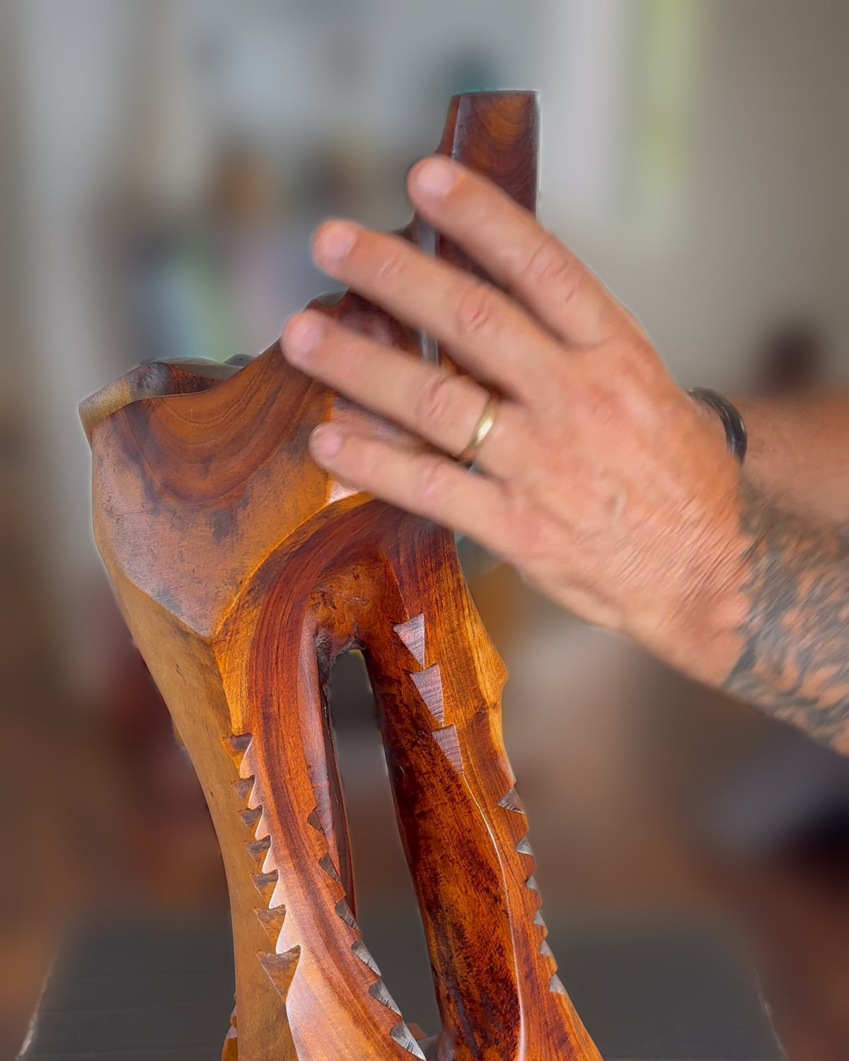 Avi Molinas's hand at the head of his carved wood sculpture Lawaiʻa, The Fisherman