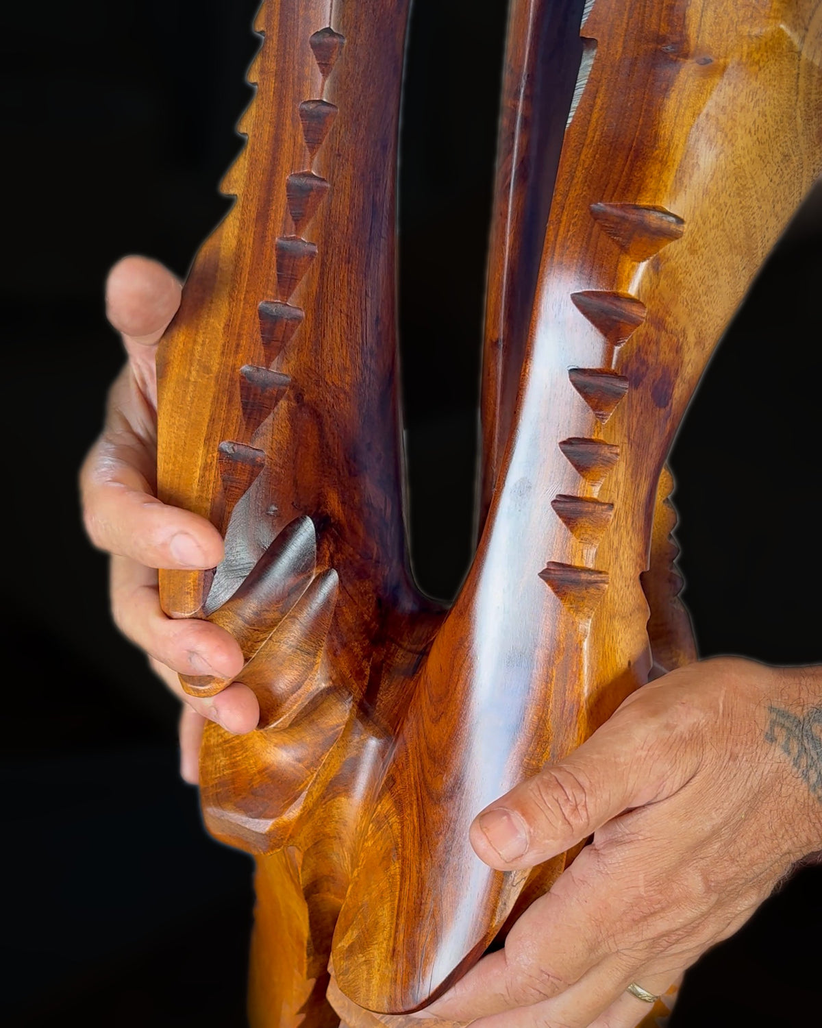 Avi's hands on the paddle-shaped hands of The Fisherman, lined with carved triangles