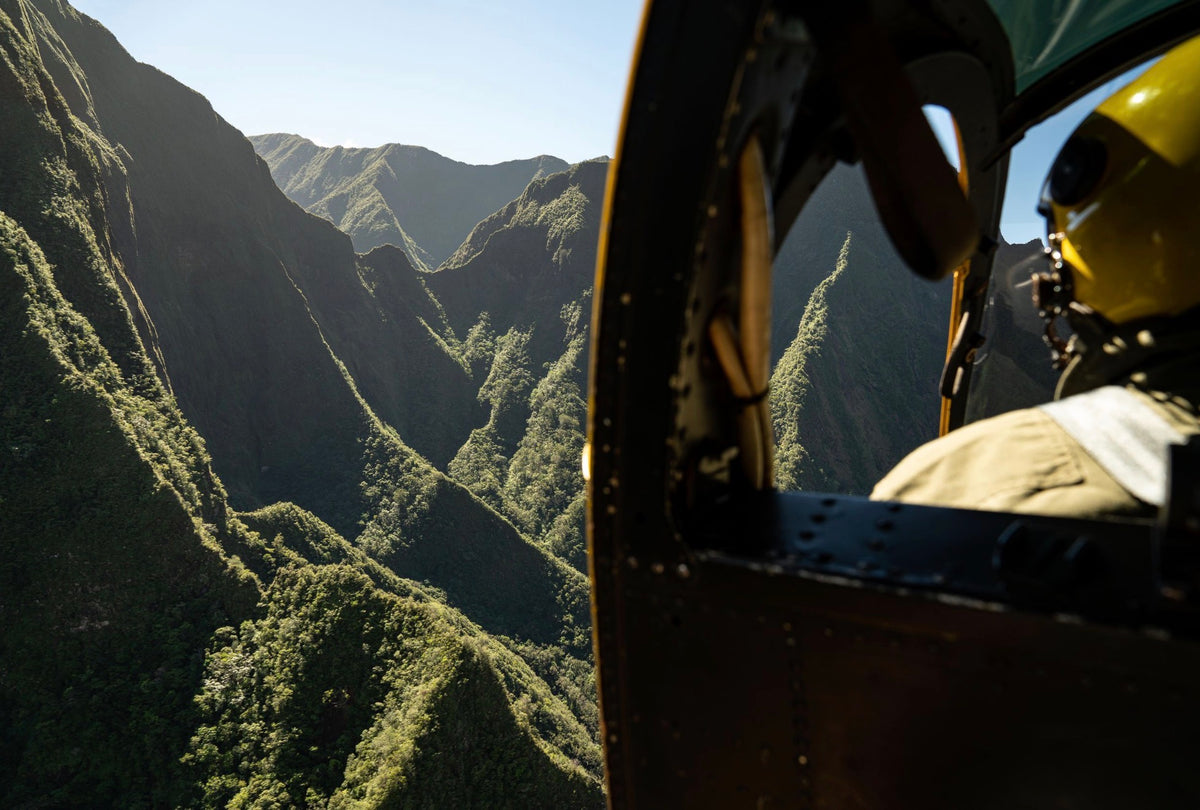 View from an open helicopter door over steep green Hawaiian valley ridges, the kind of vantage point Lance photographs from
