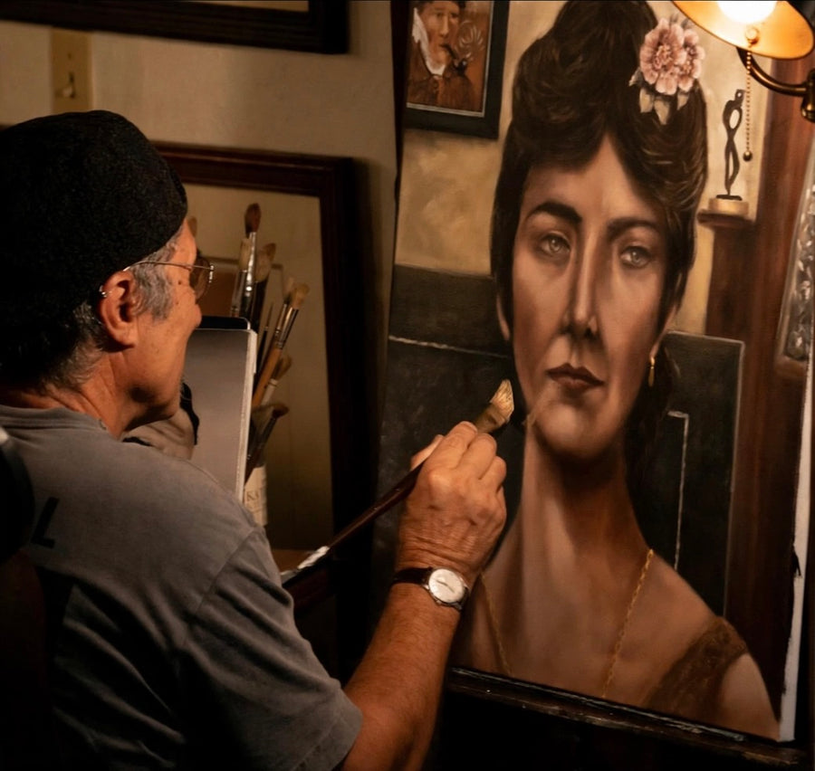 Avi Molinas at the easel, painting a portrait of a woman with flowers in her hair