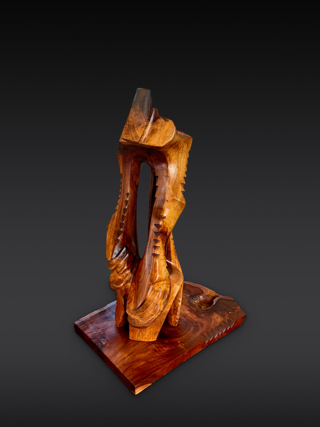Lawaiʻa | The Fisherman, carved wood sculpture by Avi Molinas: a tall open form with rows of carved notches, on a wood plinth, against a dark gray studio backdrop